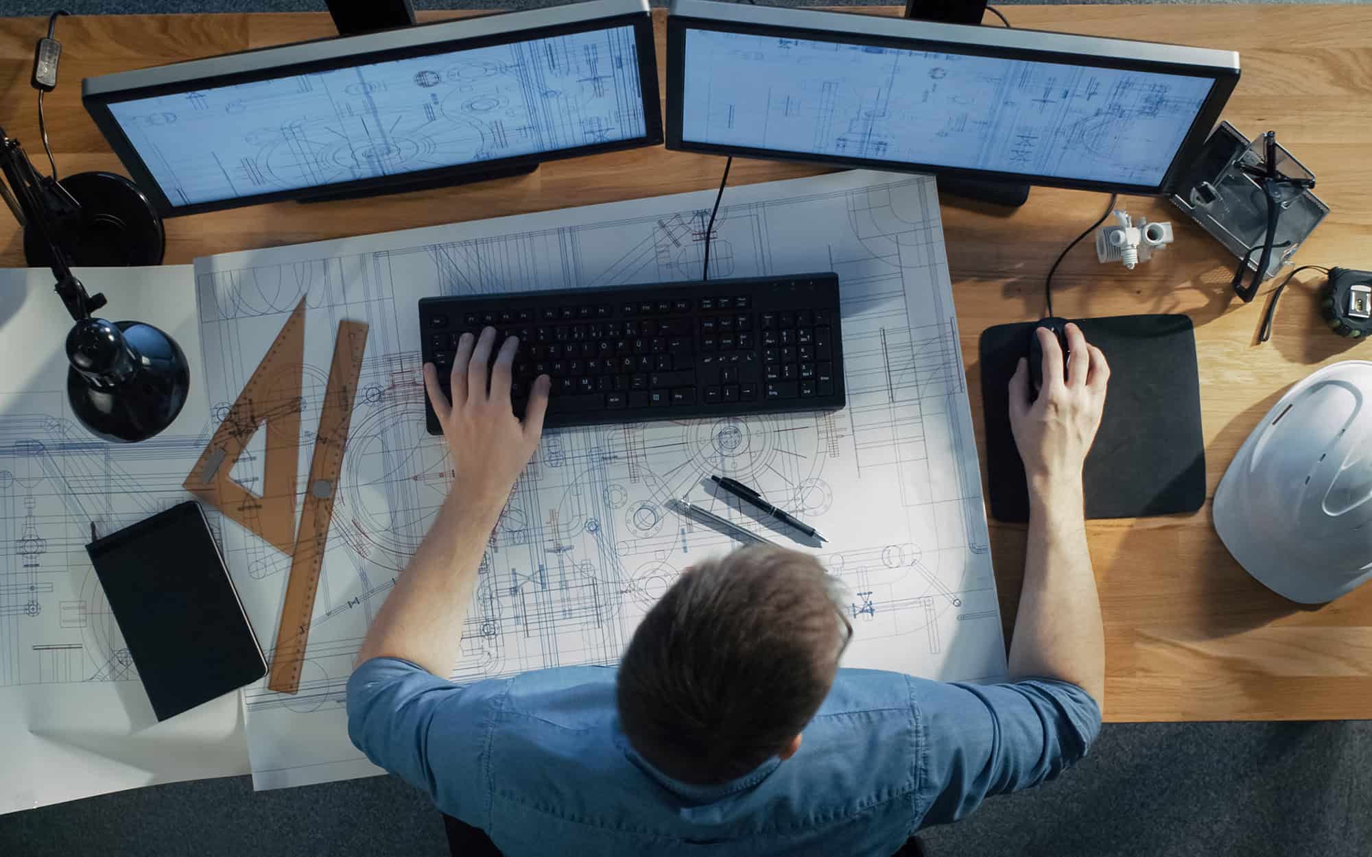 Top-down view of a man looking at two computer monitors